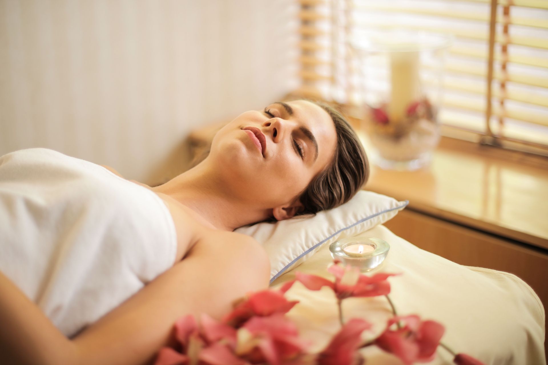Client relaxing on a massage table beside candles and flowers